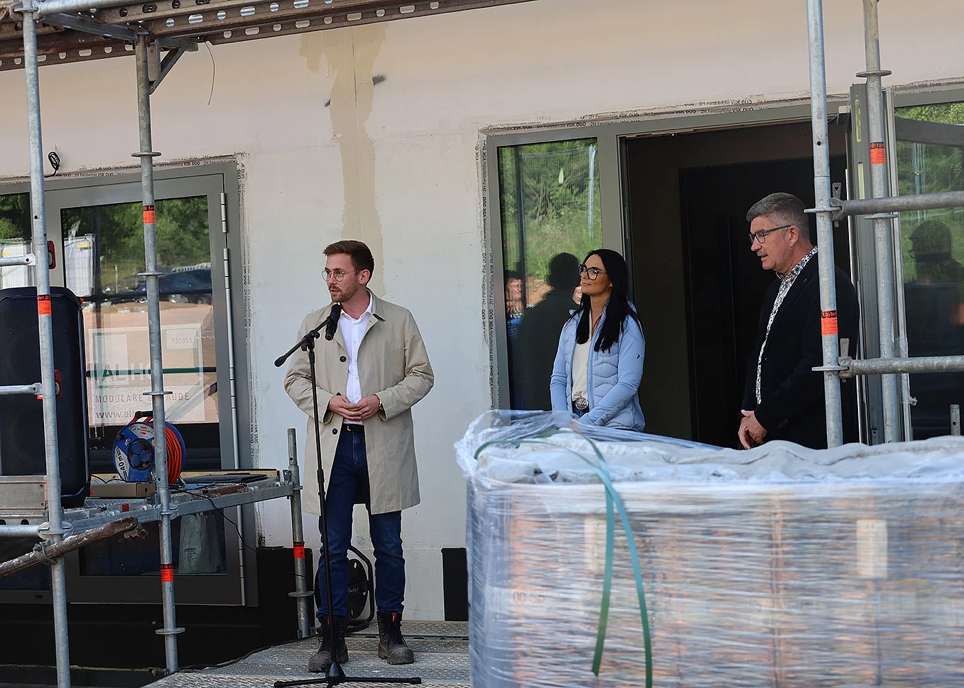 Mann spricht bei Richtfest vor Gebäude