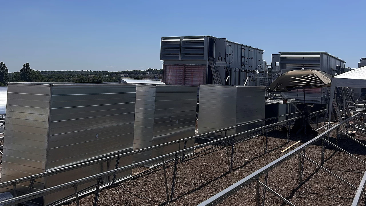 Moderne Lüftungs- und Klimaanlagen auf dem Dach eines Gewerbegebäudes mit neu installierten Lüftungskanälen und technischer Gebäudeausrüstung.