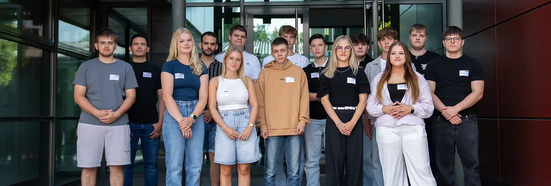Gruppenfoto der neuen ALHO Auszubildenden vor dem Eingangsbereich eines Bürogebäudes