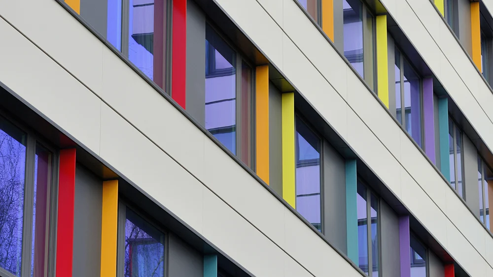 Fassadendetail eines Gebäudes mit farbigen Fensterrahmen in Rot, Gelb, Blau und Violett
