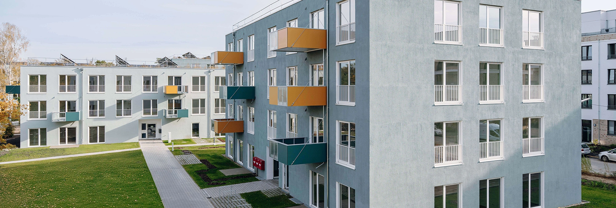Wohngebäude mit farbigen Balkonen, Spielplatz, Grünflächen und Fußwegen im Innenhof