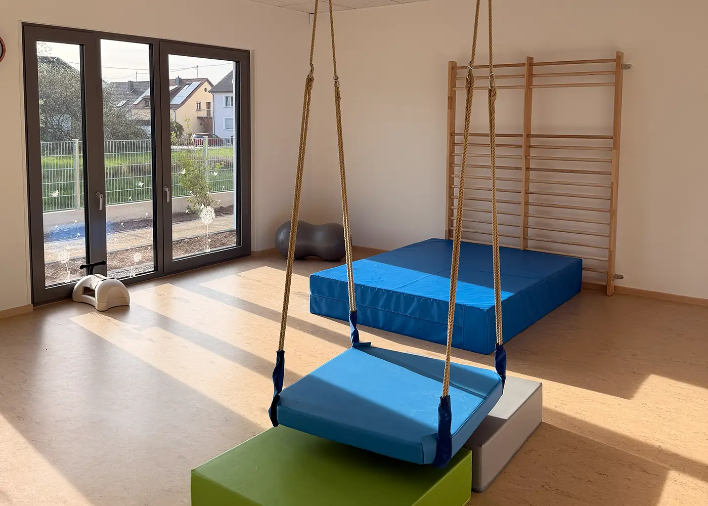 Bewegungsraum mit Hängeschaukel, weichen Matten und Kletterwand.