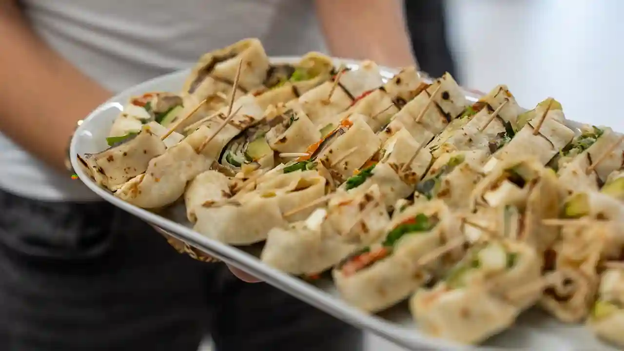 Tablett mit frisch zubereiteten Wrap-Häppchen, belegt mit Gemüse und weiteren Zutaten, serviert als Catering bei einer Veranstaltung.